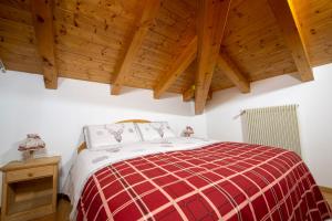 a red and white bed in a room with wooden ceilings at appartamento val di sole in Dimaro