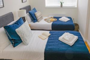 two beds in a room with blue and white pillows at Ditton Fields by condokeeper in Chesterton