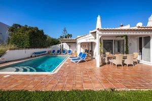 a patio with a pool and chairs and a house at Casa Madrugada in Carvoeiro