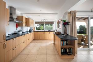 a kitchen with wooden cabinets and a black counter top at Casa Madrugada in Carvoeiro