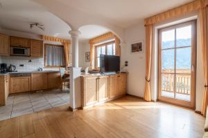 a kitchen with wooden cabinets and a large window at Gruberhof Coll in Funes