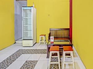 une chambre avec deux tabourets et un réfrigérateur vide dans l'établissement Capital O 91690 Moza Guest House, à Klaten