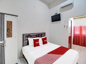 um quarto com uma cama com almofadas vermelhas em Capital O 91690 Moza Guest House em Klaten