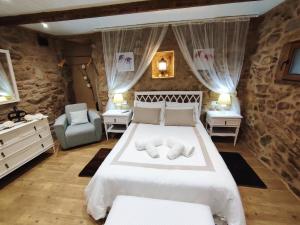 a bedroom with a large white bed and a chair at A Cuadriña in Mazaricos