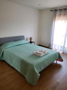 um quarto com uma cama verde com duas toalhas em Maison Fernandes 