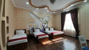 a bedroom with two beds and a painting on the wall at Villa Oasis in Bukhara