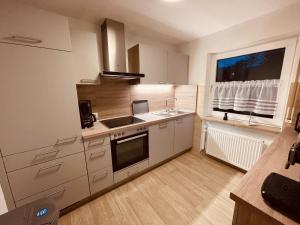 a kitchen with white cabinets and a sink and a window at Ferienwohnung Bienenkorb in Selb