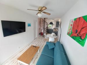 a living room with a blue couch and a flat screen tv at Duplex du Bois d'Amour in Quimper