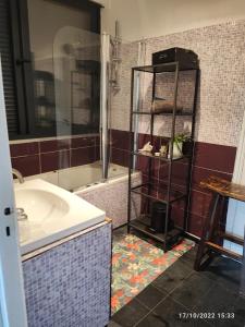 a bathroom with a tub and a sink and a shelf at chambre tt confort dans un coin de verdure près de Paris in Le Pecq