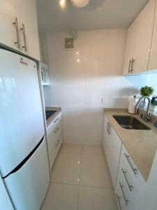 a white kitchen with a sink and a refrigerator at KASA Terrace Studio Breathtaking Ocean Views in San Juan