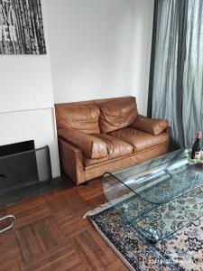 a living room with a couch and a glass table at chambre tt confort dans un coin de verdure près de Paris in Le Pecq