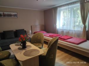 uma sala de estar com uma cama, uma mesa e cadeiras em Chatki Saturnina i pokoje em Świnoujście