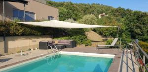 een zwembad met een witte parasol eroverheen bij Moderne Villa mit atemberaubendem Seeblick in Lisciano Niccone