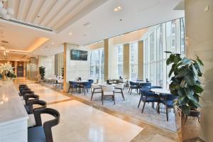un restaurante con mesas, sillas y ventanas en A&H Hotel Apartment, en Doha