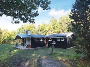 a small black house in the middle of a yard at 8 person holiday home in Roslev in Glyngøre