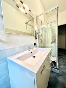La salle de bains blanche est pourvue d'un lavabo et d'une douche. dans l'établissement A 5 minuti dal mare - Dolphin Beach House, à Spotorno