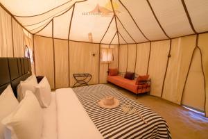 ein Zelt-Schlafzimmer mit einem Bett mit Hut darauf in der Unterkunft Erg Chebbi Camp in Merzouga