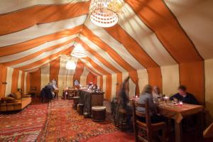 a group of people sitting at tables in a restaurant at Erg Chebbi Camp in Merzouga