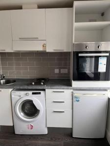 a kitchen with a washing machine and a microwave at The Serviced Accommodations in Harlow