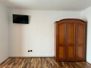 a room with a wooden cabinet and a television on a wall at M & I Apartment 3 in Târgu-Mureş
