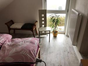 um quarto com uma cama, uma cadeira e uma planta em Ferienwohnung Anita em Jandelsbrunn