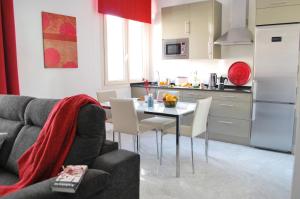 Il comprend une cuisine et un salon avec une table et des chaises. dans l'établissement Sevilla Central Suites Apartamentos Puerta Jerez, à Séville