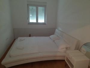Una cama blanca en una habitación con ventana. en NinaRich, en Trebinje