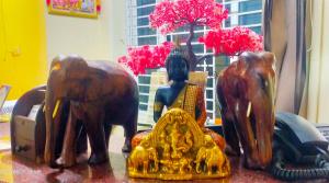 a table topped with wooden statues of elephants and a vase at Madurai Grands Inn in Madurai