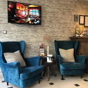 two blue chairs and a television on a brick wall at Hotel Divan in Sarajevo