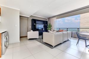 sala de estar con sofá blanco y ventana grande en La Vista Dream Apartments Luxury & Modern with City View and Inverter back up!, en Johannesburgo