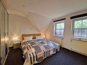 a bedroom with a bed and two windows at Ferienhaus Ankerplatz im Bootshaus in Neßmersiel