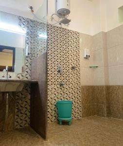 a bathroom with a shower with a green bucket in it at Hotel Meerana in Jaisalmer