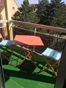 einen roten Tisch und Stühle auf dem Balkon in der Unterkunft Charmant appartement 2 pièces Mundolsheim in Mundolsheim