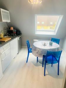 eine Küche mit einem Tisch und blauen Stühlen in der Unterkunft Charmant appartement 2 pièces Mundolsheim in Mundolsheim