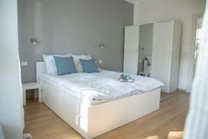 uma cama branca com almofadas azuis e um espelho em Apartmani 64 em Sombor