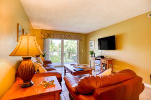 een woonkamer met 2 banken en een televisie bij Ocean view condo in beachfront resort with WiFi, central AC, 2 pools, & tennis in St. Augustine