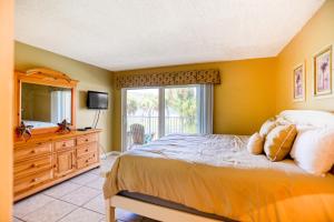 een slaapkamer met een bed, een ladekast en een raam bij Ocean view condo in beachfront resort with WiFi, central AC, 2 pools, & tennis in St. Augustine +24 foto's