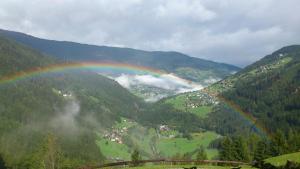a rainbow in the middle of a valley with a town at Berghütte Graslehn in Jerzens