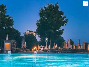 維也納的住宿－Parkblick / Therme Wien / Fitnessraum / Terrasse / U-Bahn，夜间带遮阳伞的大型游泳池