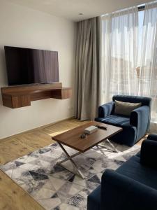 uma sala de estar com uma televisão, um sofá e uma mesa em شرفة em Riade