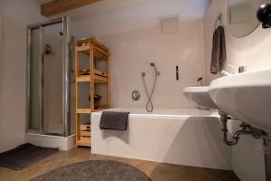 a bathroom with a tub and a sink and a shower at FLOW Village Apartment in Sarntal