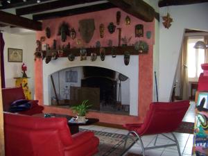 ein Wohnzimmer mit einem Kamin und roten Stühlen in der Unterkunft Grande maison atypique in Le Burgaud