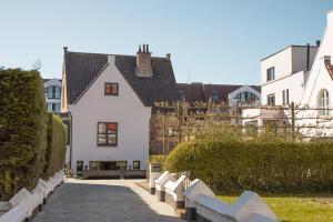 una casa blanca con una valla en una calle en Nieuw app met tuin en terras, gratis parking, aan zee, vlakbij Brugge en Duinbergen