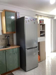 a kitchen with a white refrigerator and green cabinets at Παραλιακό διαμέρισμα με αυλή in Gythio