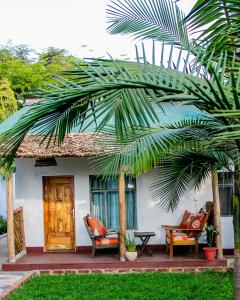 a house with two chairs and a palm tree at Blue elephant villas in Arusha