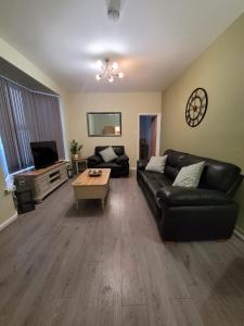 sala de estar con sofá de cuero negro y mesa en Handpost Retreat en Newport