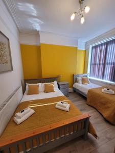 Duas camas num quarto com paredes amarelas em Handpost Retreat em Newport