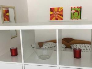 a white shelf with a bowl and two red candles at Ferienwohnung Am Wald in Schönwald