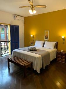 a bedroom with a bed with a bench in it at Pousada Villa Real in Tiradentes