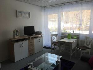 a living room with a tv and a table with a table at Ferienwohnung Am Wald in Schönwald